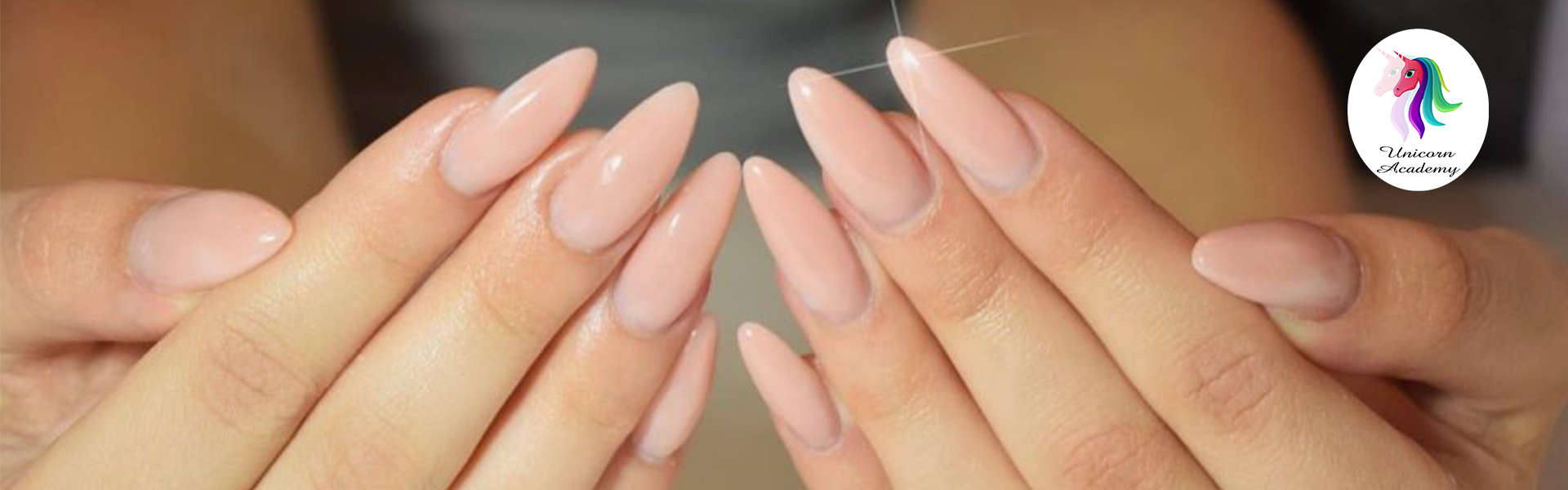 A photo of a hand with long, nude-colored nail extensions. The nails have a high-gloss finish.