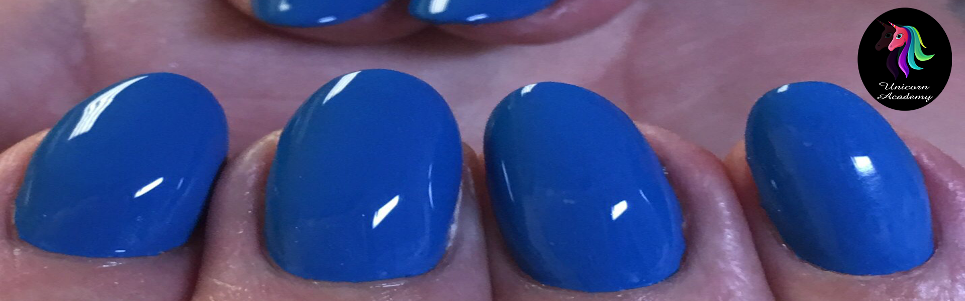 A photo of a hand with short, shiny blue nail extensions. The nails have a smooth, flawless finish.